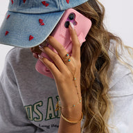 Chaîne de doigt dorée en acier inoxydable avec perles turquoise et petite croix, portée sur main féminine.