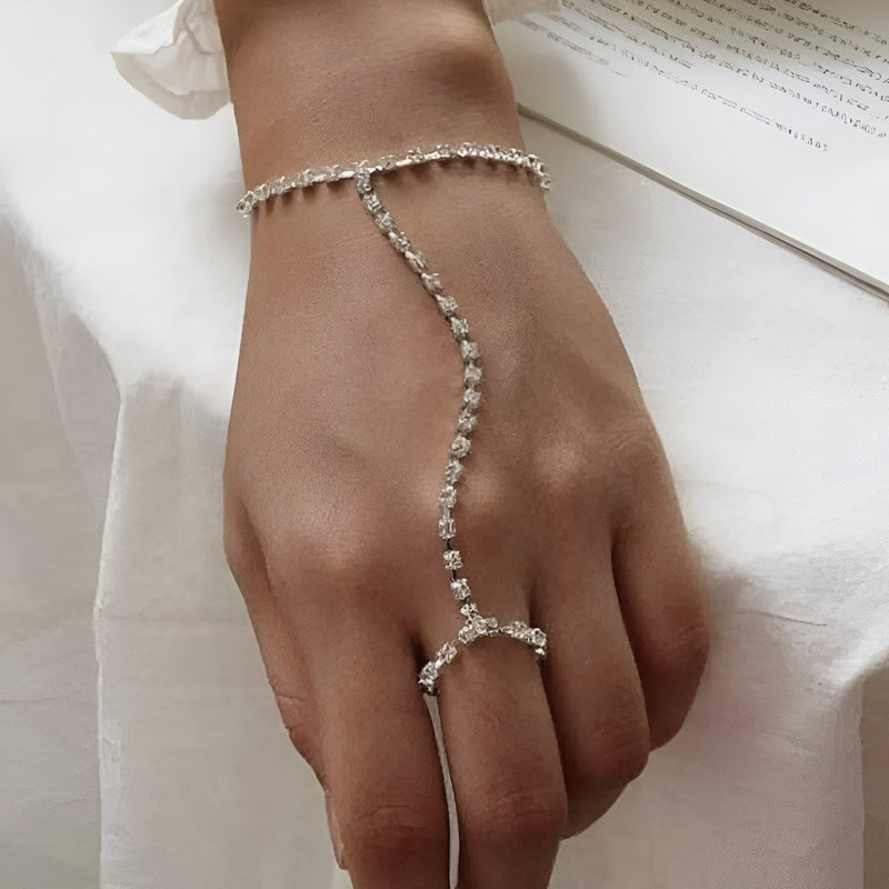 Bijou de main en acier inoxydable argenté avec zirconiums, bracelet et anneau reliés par une chaîne scintillante.