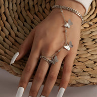 Bijou de main argenté en acier inoxydable avec motif papillons et chaîne délicate sur main féminine.