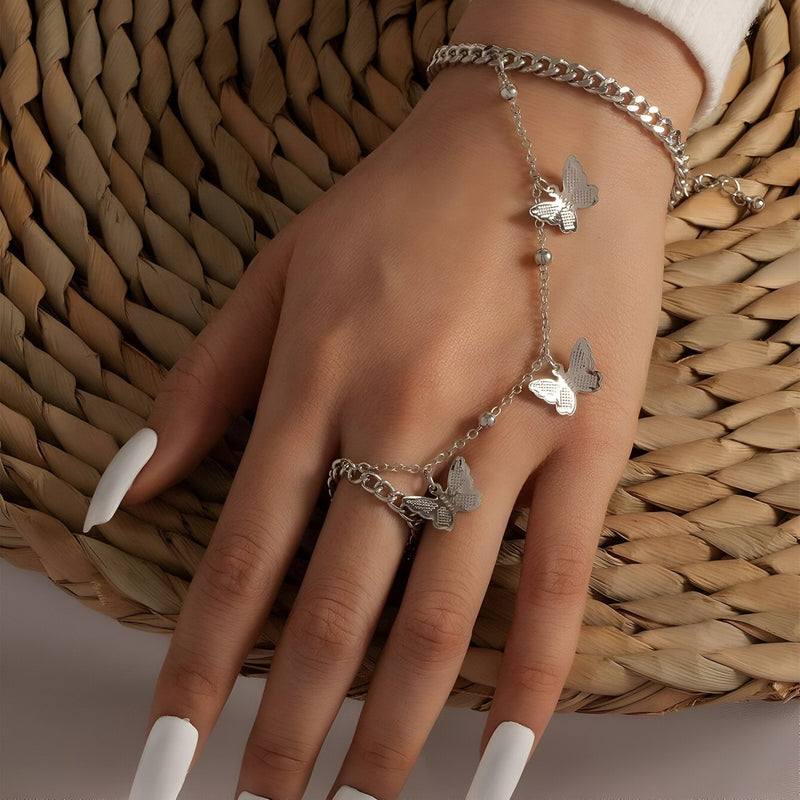 Bijou de main argenté en acier inoxydable avec motif papillons et chaîne délicate sur main féminine.