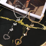Bijou de main en acier inoxydable avec chaîne fine et trois papillons délicats, disponible en or et argent.