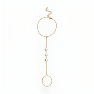 Bijou de main en acier inoxydable doré avec chaîne fine et anneaux ronds décorés de petits zirconiums blancs.