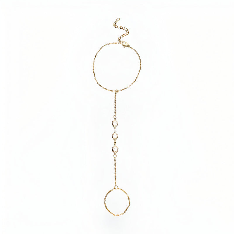 Bijou de main en acier inoxydable doré avec chaîne fine et anneaux ronds décorés de petits zirconiums blancs.