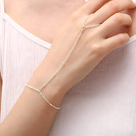 Bijou de main en acier inoxydable argenté avec bracelet et chaîne fine reliant doigt et poignet.