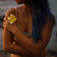 Bijou de main en acier inoxydable or avec chaîne reliant un bracelet à un anneau fin, porté sur une main féminine avec fleur .