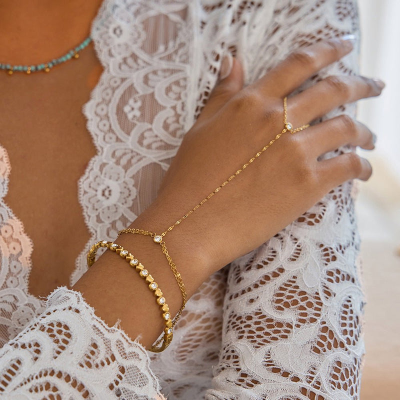 Chaîne de doigt en acier inoxydable plaqué or avec maille fine, bracelet assorti sur poignet, style délicat et brillant.