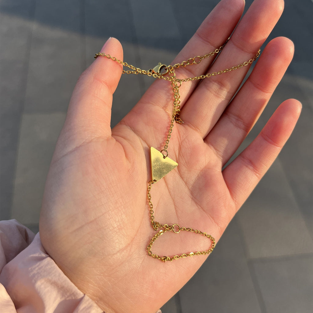Bijou de main en acier inoxydable doré avec motif triangle et chaîne fine élégante.