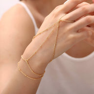 Bijou de main multi-rangs en acier inoxydable doré, chaînes fines élégantes entourant le poignet et le doigt.