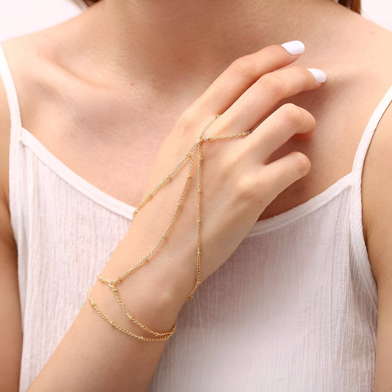 Bijou de main multi-rangs en acier inoxydable doré, chaîne fine et anneaux élégants sur main féminine.