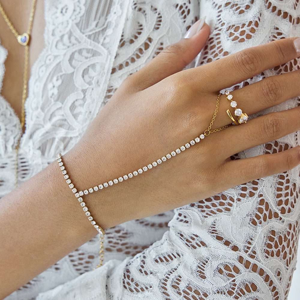 Chaîne de main dorée à l’or fin avec zircon scintillant, design élégant reliant le poignet au doigt.