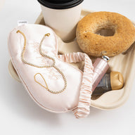 Chaîne de main dorée à l’or fin avec zircon scintillant, fine et élégante sur tissu rose pâle.