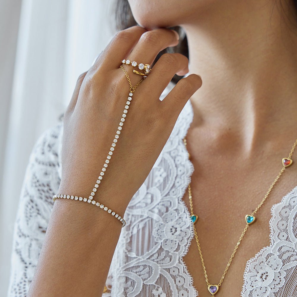 Chaîne de main dorée à l’or fin ornée de petits zircons scintillants, design élégant reliant bague et bracelet, porté sur.
