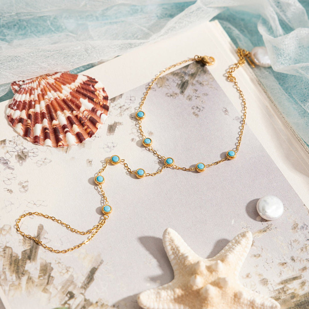 Chaînette de main dorée en acier inoxydable avec pierres turquoise ovales élégantes, design délicat sable.