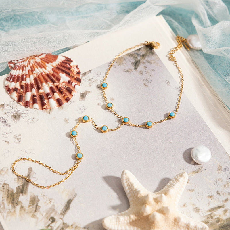 Chaînette de main dorée en acier inoxydable avec pierres turquoise ovales élégantes, design délicat sable.