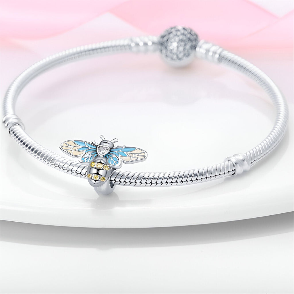 Bracelet argent avec charm abeille bleu et cœur doré orné de strass blancs.