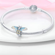 Bracelet argent avec charm abeille bleu et cœur doré orné de strass blancs.