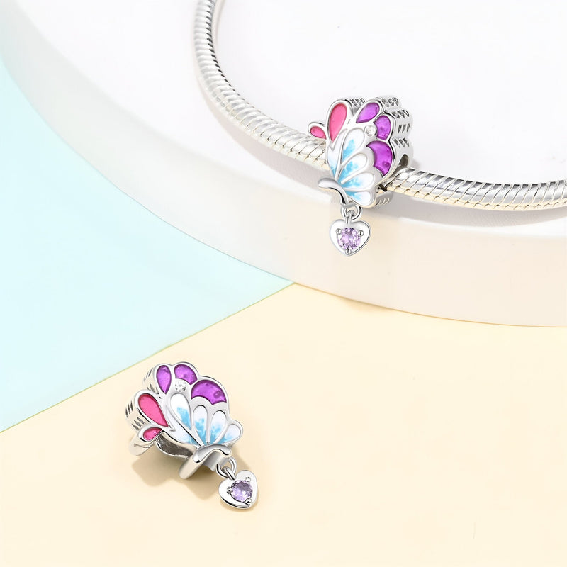 Charm aile de papillon en argent avec émail rose, bleu, violet et pendentif cœur violet.