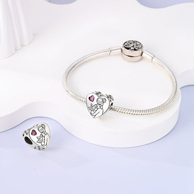 Bracelet argenté avec un charm cœur orné de gravure mère et enfant et pierre rose</s>.