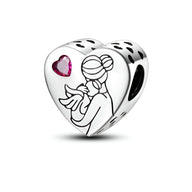 Charm en argent en forme de cœur avec gravure d'une mère tenant un bébé et un petit cœur rose incrusté.