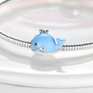 Charm baleine bleue en émail avec détails argentés, sur bracelet serpent argenté.