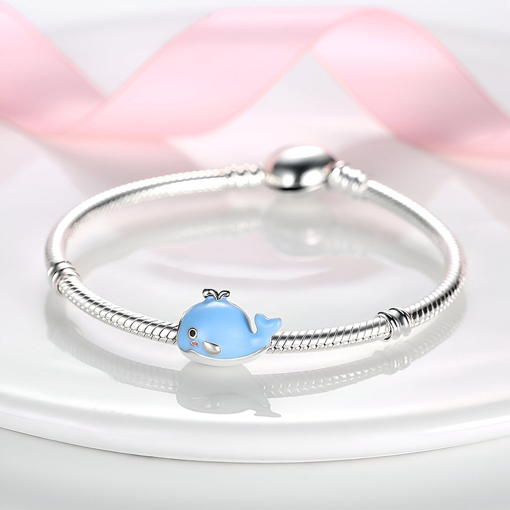 Bracelet argenté avec charm baleine bleue et détails blancs pour femme.