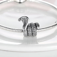 Charm cobra argenté détaillé en forme de serpent enroulé sur un bracelet serpent fin.