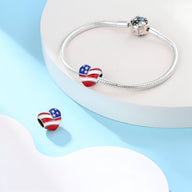 Charm en forme de cœur aux couleurs du drapeau américain, orné d'étoiles et rayures sur bracelet argenté.