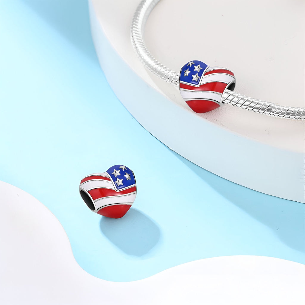 Charm en forme de cœur avec drapeau américain rouge, blanc et bleu, étoiles et rayures sur bracelet argenté.
