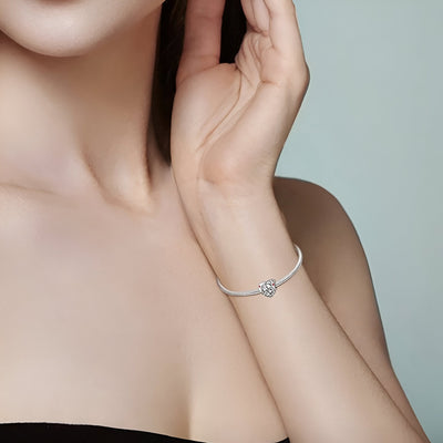 Bracelet fin argent avec charm cœur orné de diamants porté au poignet féminin.