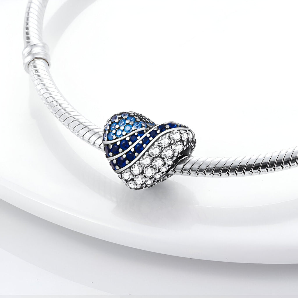 Charm cœur en métal argenté avec zirconiums bleus et blancs, modèle Drusilla, brillant et élégant.
