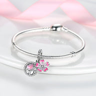 Bracelet argent avec pendentifs cœur rose et marguerite rose détaillée.
