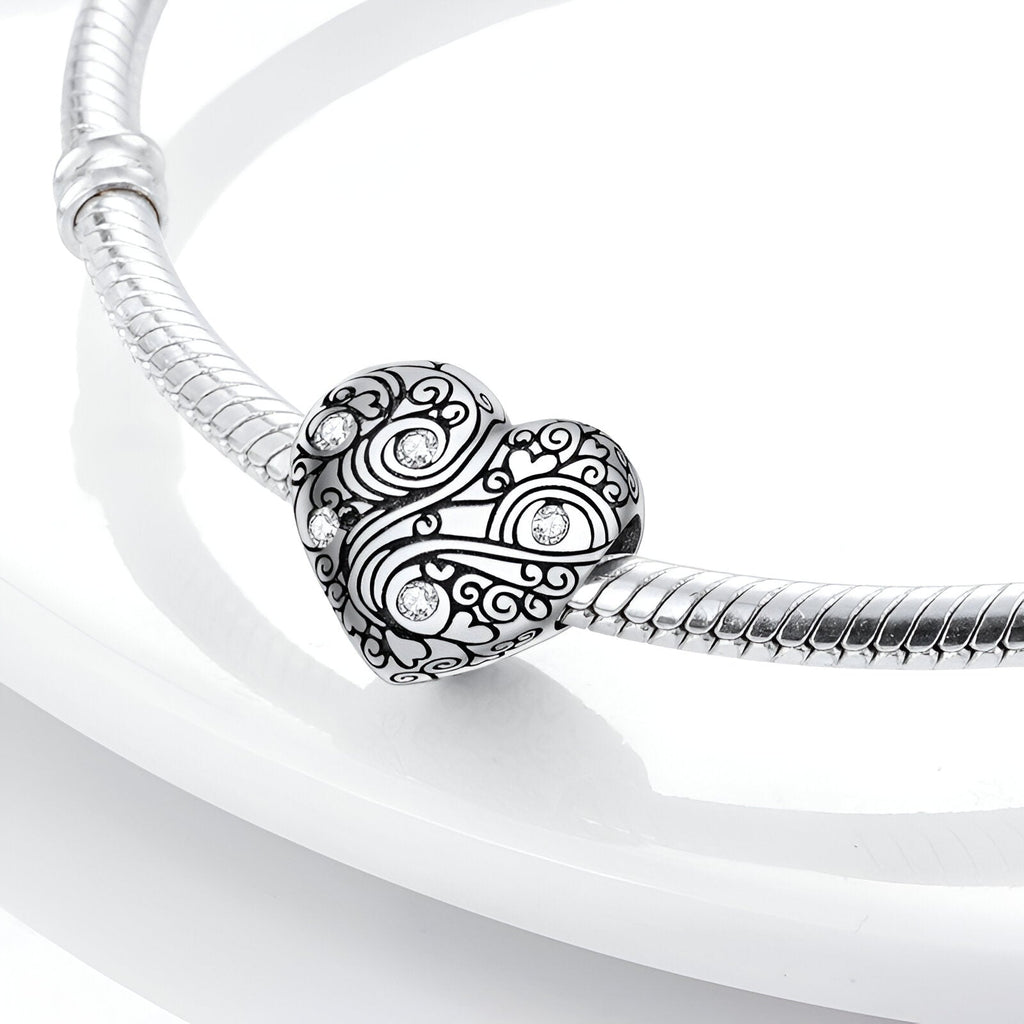 Bracelet serpent argent avec charm cœur Leontine gravé de motifs floraux et arabesques.