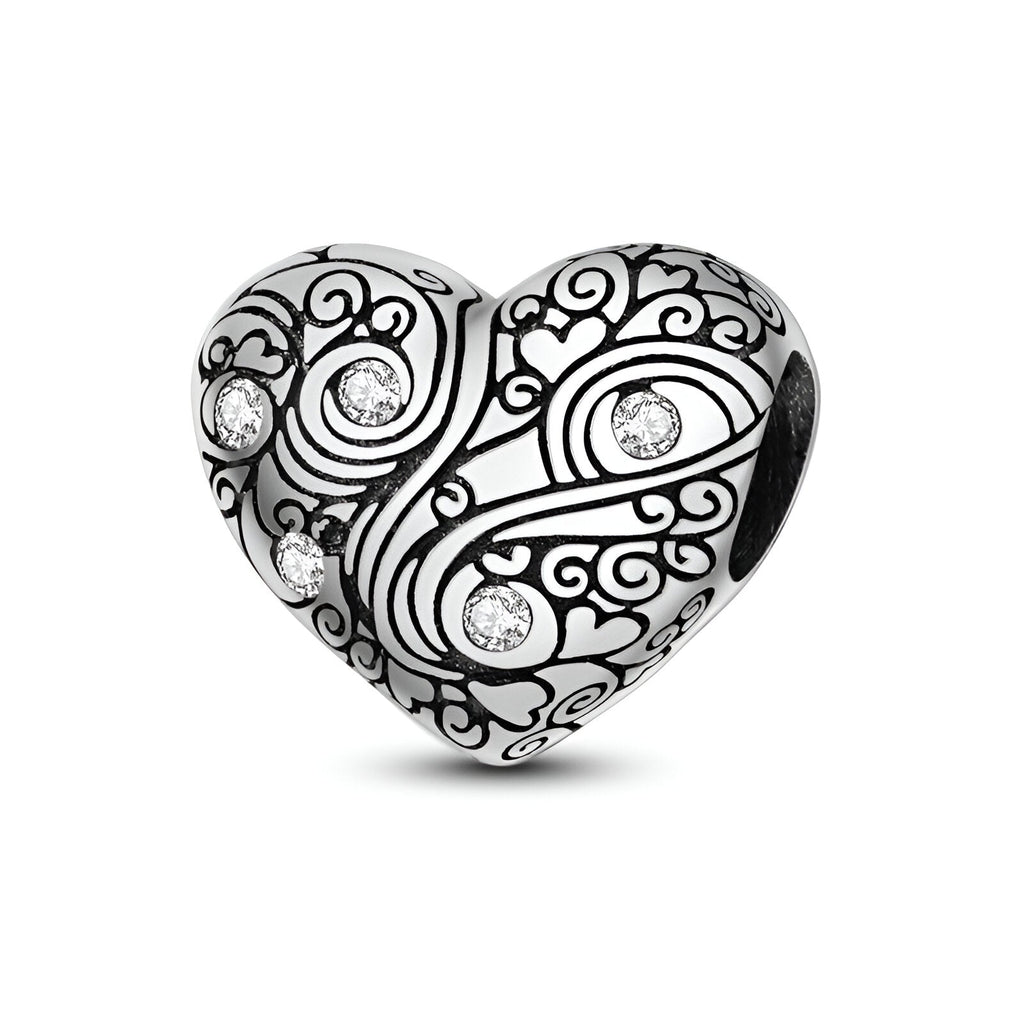 Charm cœur en argent gravé de motifs arabesques avec cinq petits strass brillants.