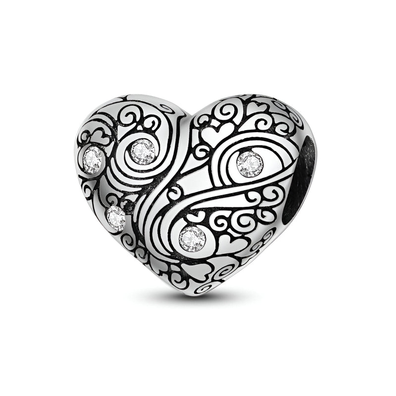 Charm cœur en argent gravé de motifs arabesques avec cinq petits strass brillants.