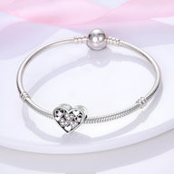 Bracelet argent avec charm coeur incrusté de petits coeurs roses scintillants.