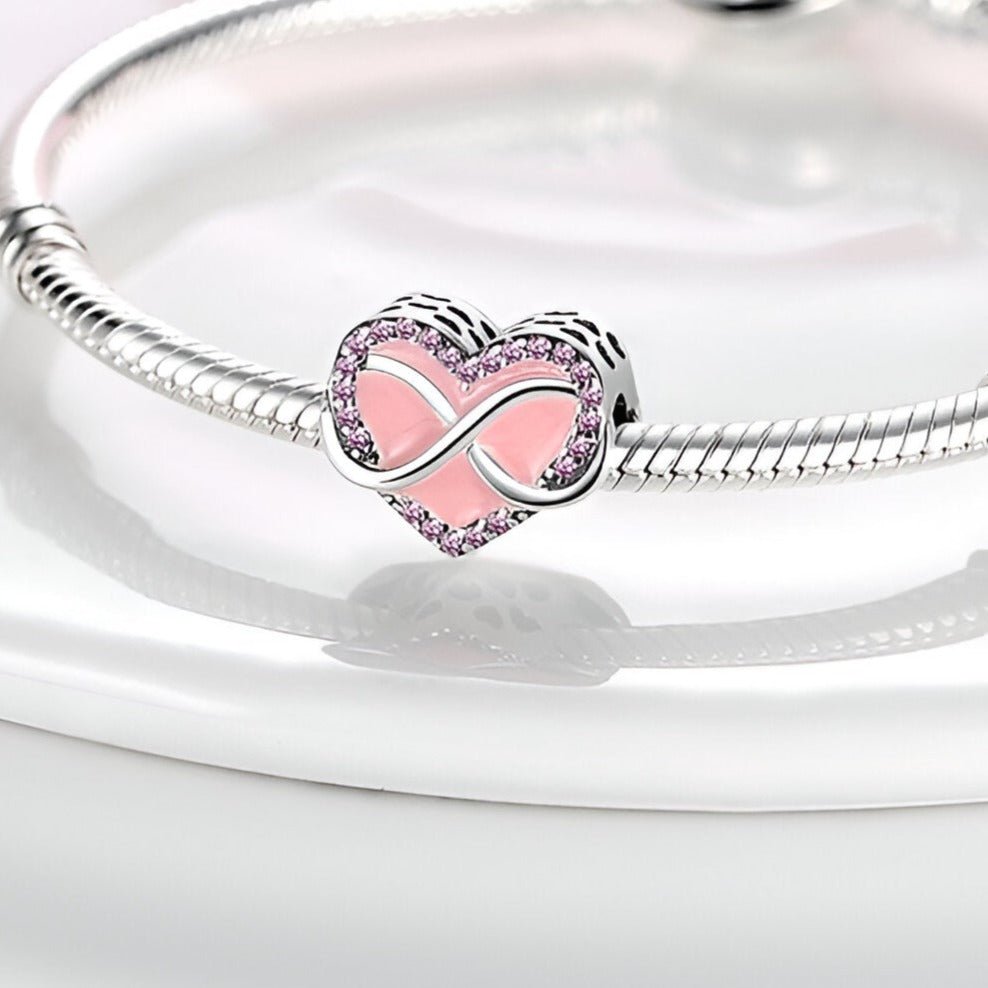Charm en forme de cœur rose avec symbole infini en métal argenté sur bracelet serpent argenté.