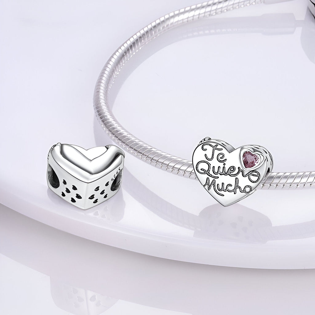 Charm coeur en argent avec inscription "Te Quiero Mucho" et petite rose rose, sur bracelet serpent argenté.