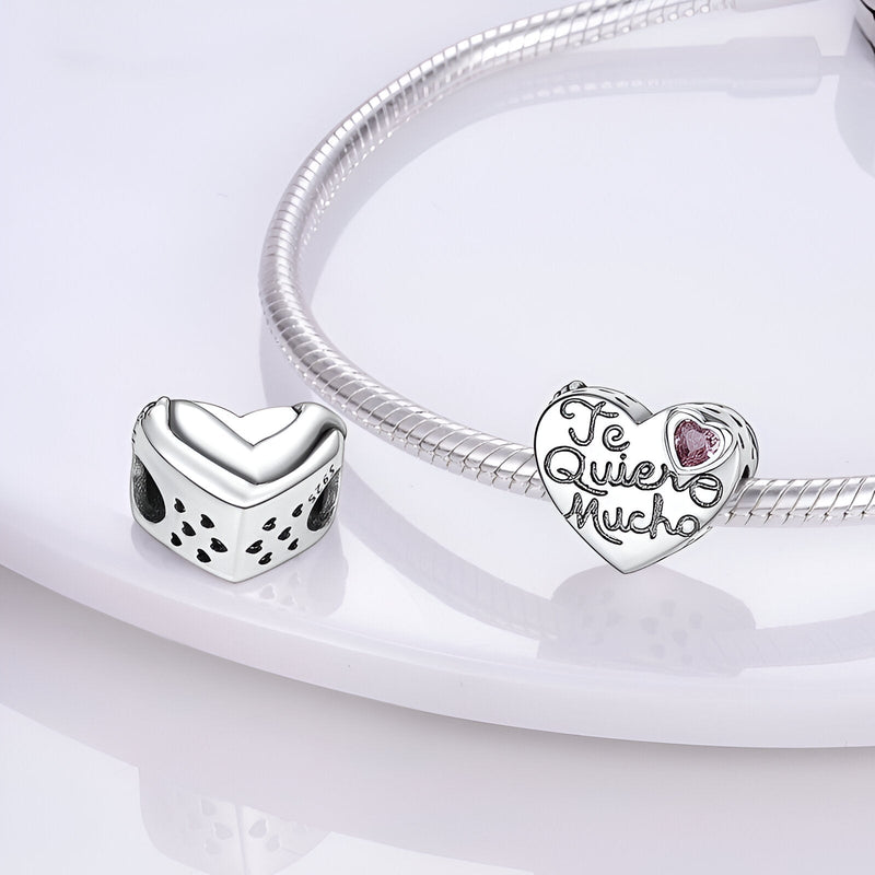Charm coeur en argent avec inscription "Te Quiero Mucho" et petite rose rose, sur bracelet serpent argenté.