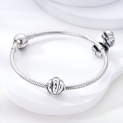 Bracelet argenté avec charm coquillage brillant orné de petits cristaux.