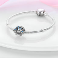 Bracelet argenté avec charm coquillage ajouré orné de perles et étoiles bleues.
