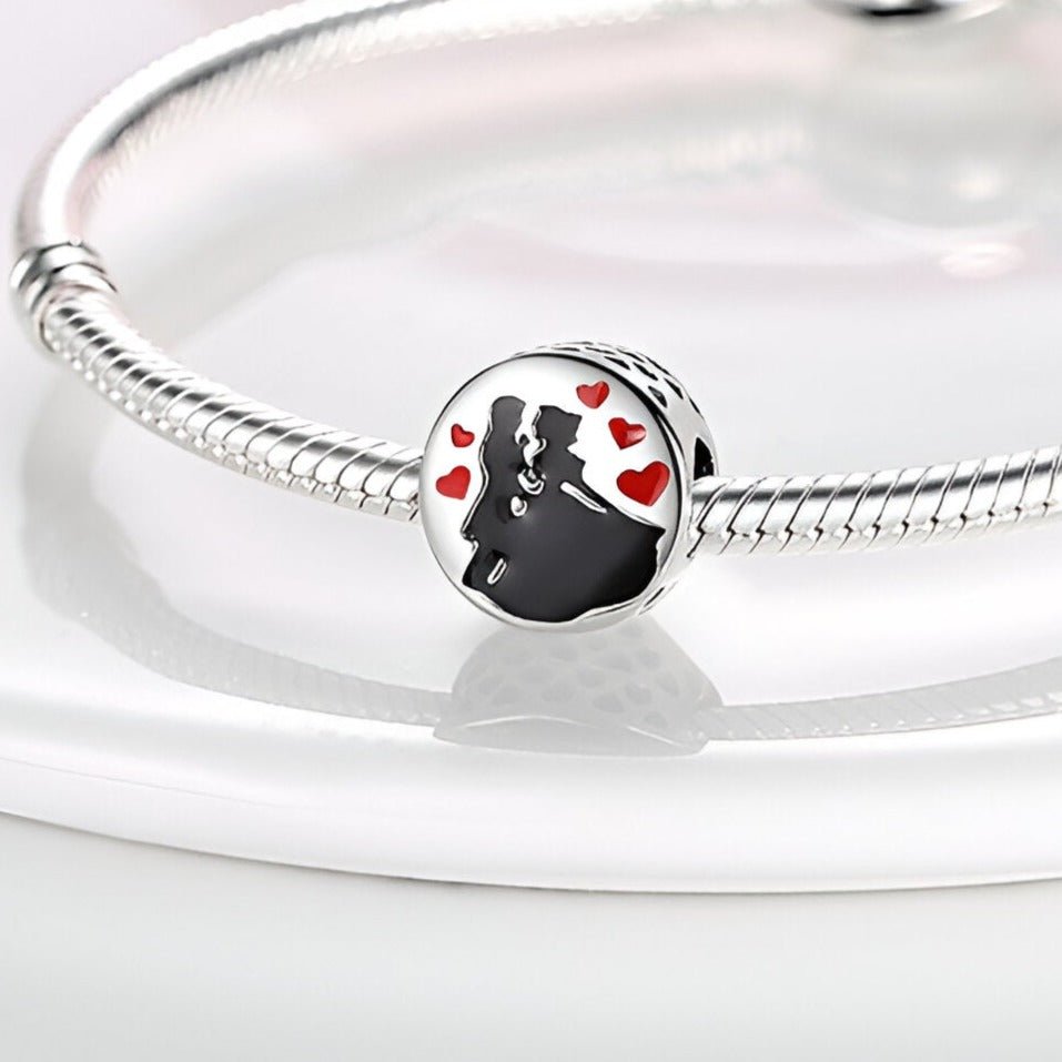 Charm argenté représentant un couple dansant entouré de petits cœurs rouges, sur bracelet serpent argenté.