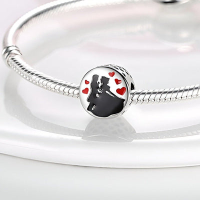 Charm argenté représentant un couple dansant entouré de petits cœurs rouges, sur bracelet serpent argenté.