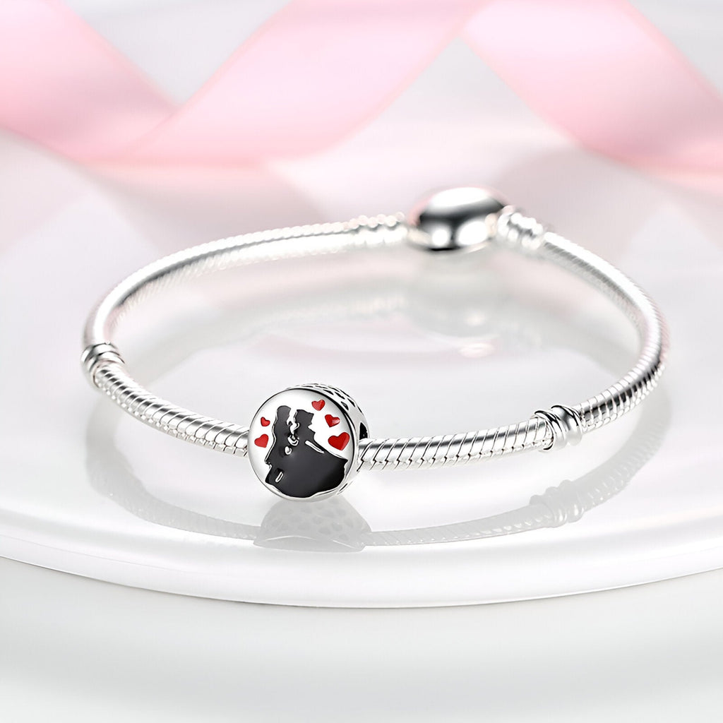 Bracelet argenté avec charm couple dansant en silhouette noire et détails rouges sur fond blanc.