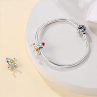 Charm fusée spatiale multicolore en métal sur bracelet serpent argenté fin.