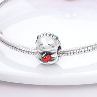 Charm en forme de hérisson argenté tenant une pomme rouge sur un bracelet serpent en argent.