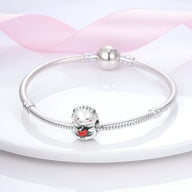 Bracelet argent avec charm hérisson détaillé tenant un cœur rouge brillant.