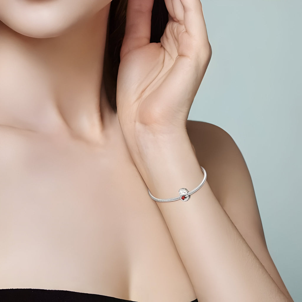 Charm bracelet argent avec pendentif hérisson mignon émaillé blanc et rouge sur poignet féminin.