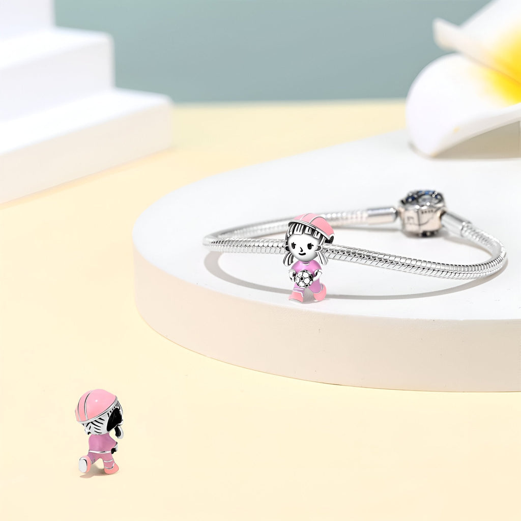 Charm femme en argent avec joueuse de football en tenue rose détaillée sur bracelet serpent.