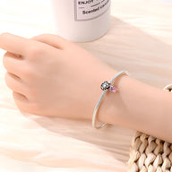 Bracelet argenté fin avec charm ballon de football noir et blanc et petite étoile rose en pendentif.