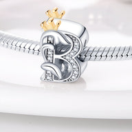 Charm lettre B en argent avec pierres blanches et couronne dorée sur bracelet serpent.